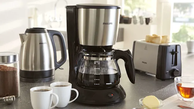 Keukenopstelling met koffiezetapparaat, waterkoker, broodrooster, koffie, thee en boter.