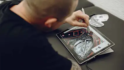 Een persoon tekent een zwart-wittekening op een tablet met een stylus, op een donker oppervlak.