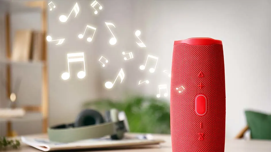 Een rode luidspreker staat op een tafel met muzieknoten die omhoog zweven, en een koptelefoon is op de achtergrond te zien.