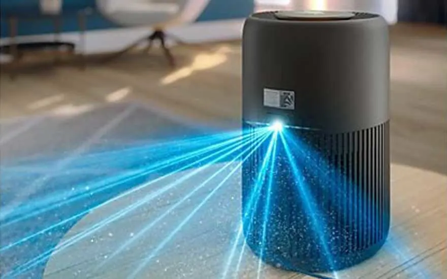Een compacte donkere luchtreiniger straalt heldere blauwe lichtstralen uit langs het oppervlak, terwijl zwevende stofdeeltjes zichtbaar worden weggefilterd.