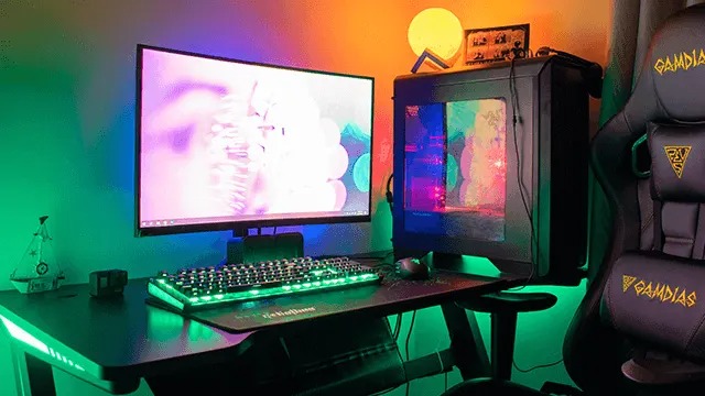Gamingbureau met felgroene verlichting, één monitor, glazen pc-kast, RGB-toetsenbord en ergonomische Gamdias-stoel.