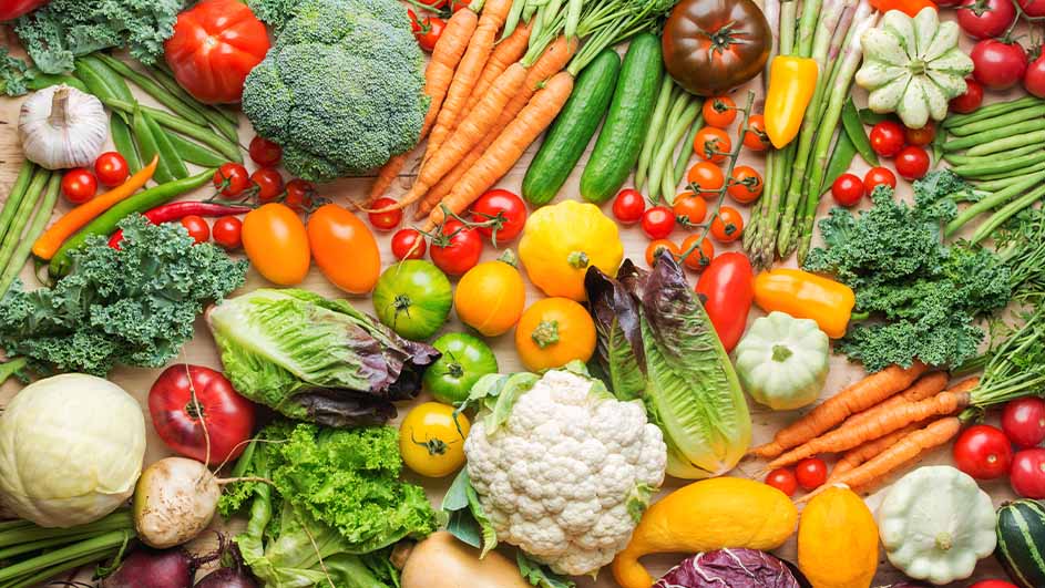 Een assortiment verse groenten, waaronder broccoli, wortelen, tomaten, sla, asperges, courgette en bloemkool.