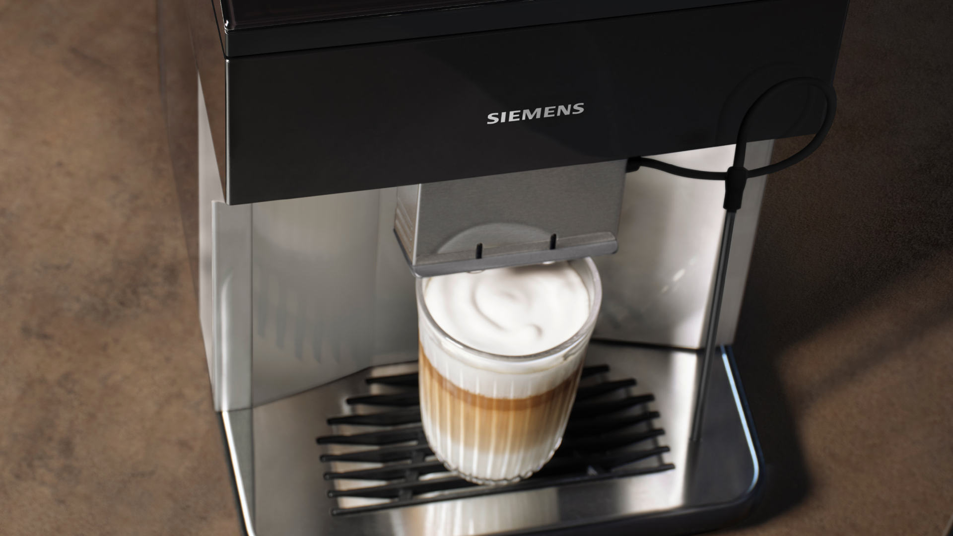Een Siemens koffiemachine vult een ribbelglas met koffie en melkschuim op een zwart rooster.