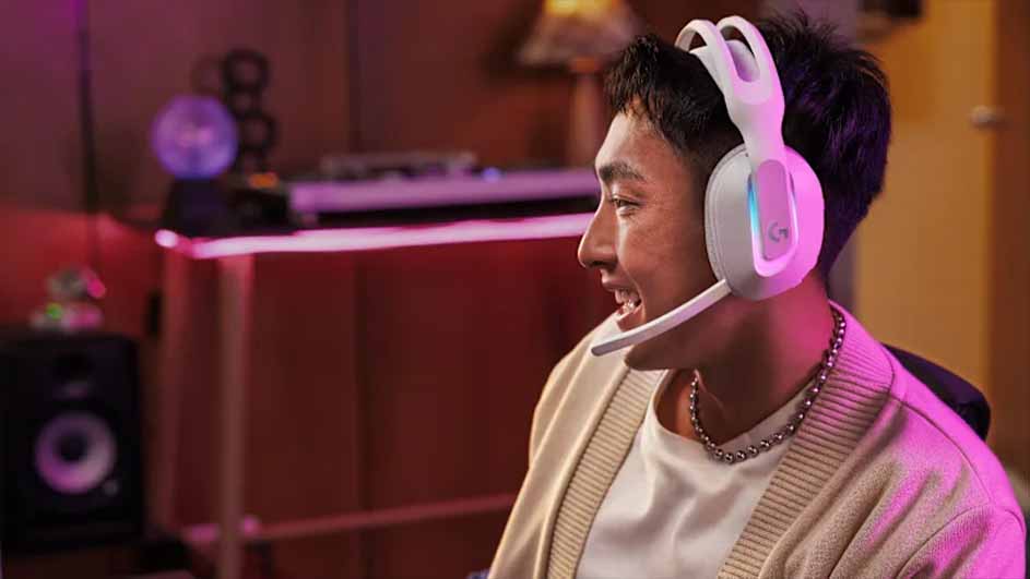 Lachende man met een witte Logitech G-gamingheadset met microfoon, zittend in een warm verlichte kamer.