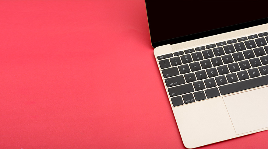 Een laptop met een zwart scherm en toetsenbord ligt op een rode achtergrond. Het toetsenbord is wit met zwarte toetsen.