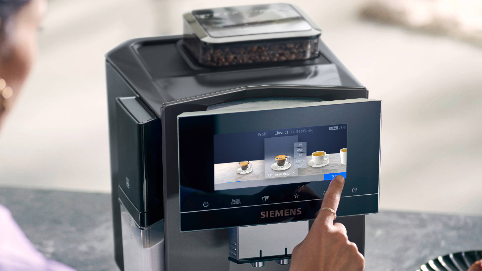 Een Siemens koffiemachine met een touchscreen waarop koffie-opties staan afgebeeld, een hand selecteert een optie.