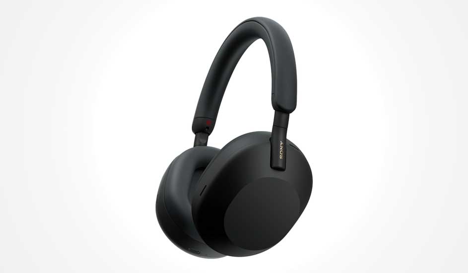 Sleek black over ear wireless headphones with a smooth padded headband, rounded earcups and a minimalist modern design on a pale background.