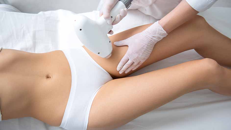 Een vrouw ligt op een wit laken terwijl een persoon met handschoenen een laserbehandeling uitvoert op haar been.