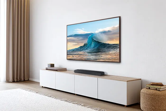 Woonkamer met witte kast, tv met oceaanafbeelding, beige gordijnen en een wit vloerkleed.
