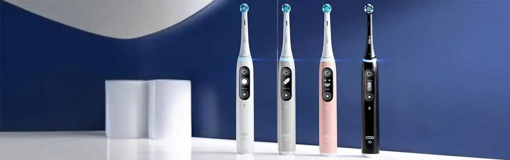 Vier Oral-B iO Series 6 elektrische tandenborstels staan rechtop op une witte plank tegen een blauwe achtergrond, strak en modern.