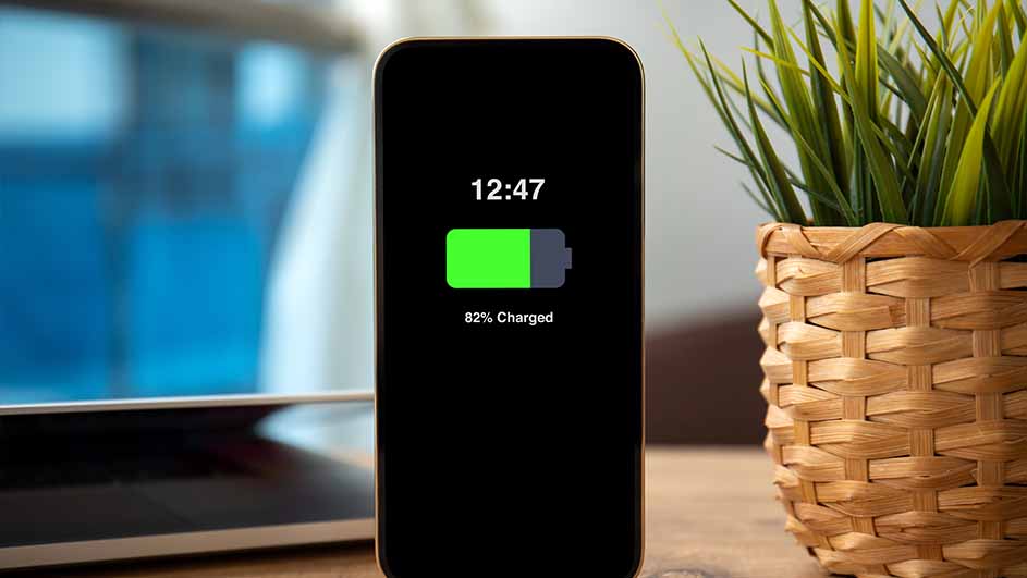 Een telefoon met een zwart scherm toont een batterij van 82% en een klok van 12:47, naast een plant in een pot.