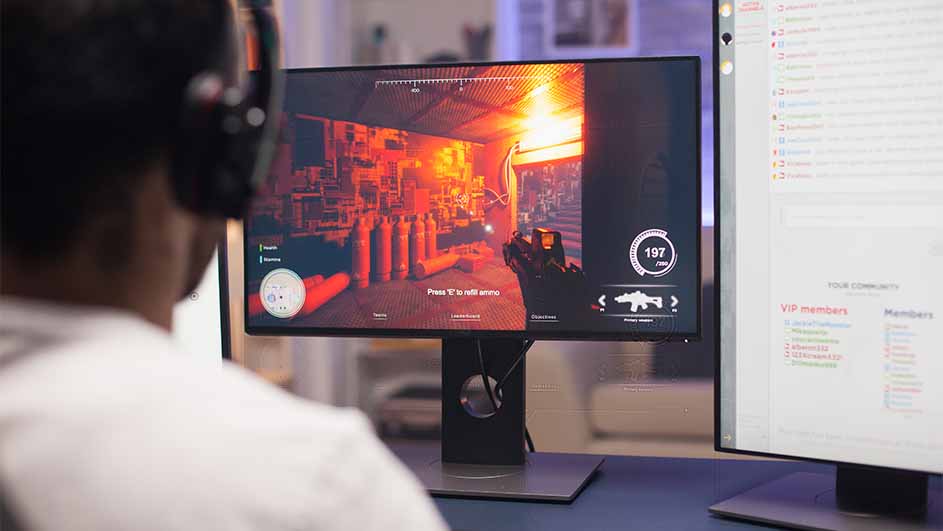 Een persoon met een koptelefoon speelt een schietspel op een groot scherm, met een tweede scherm ernaast met tekst.