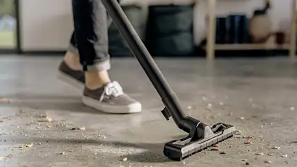 Someone is vacuuming the floor with a Kärcher vacuum cleaner, picking up visible dirt and debris.