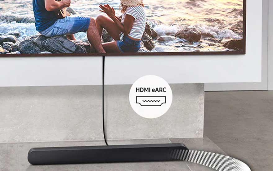 Zwarte soundbar onder een wand-tv, verbonden via HDMI eARC, met kabel zichtbaar en strandscène op het scherm.