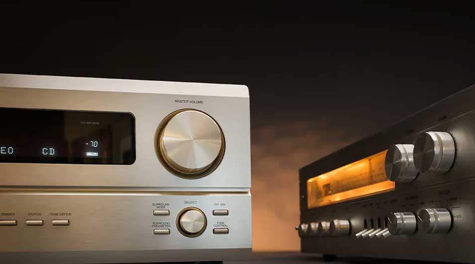 Two silver audio receivers with dials and buttons, one showing CD and volume output against a dark background.