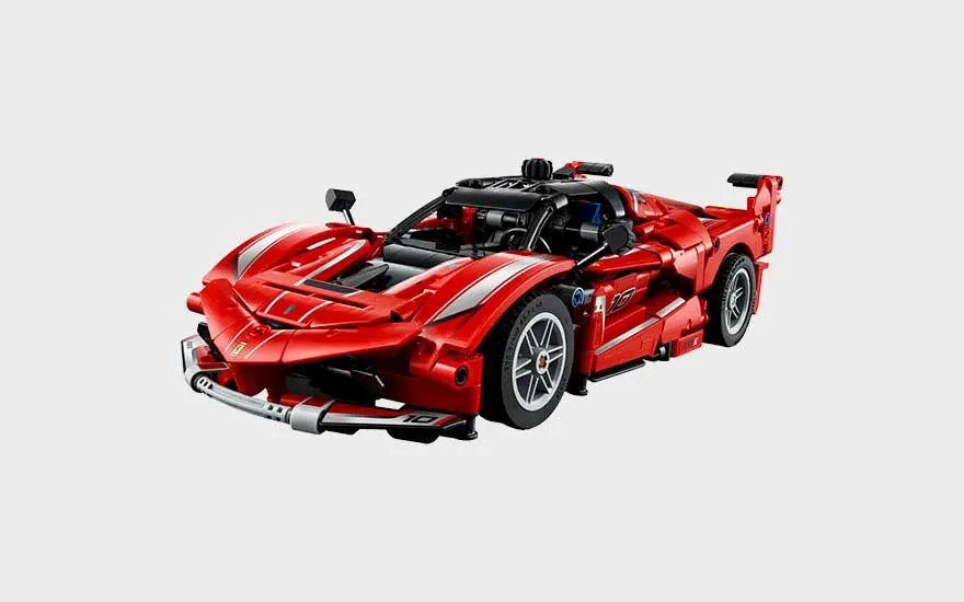 Rode LEGO Ferrari-racewagen met witte strepen, grote spoiler, sportieve lijnen en gedetailleerde cockpit op grijze achtergrond.