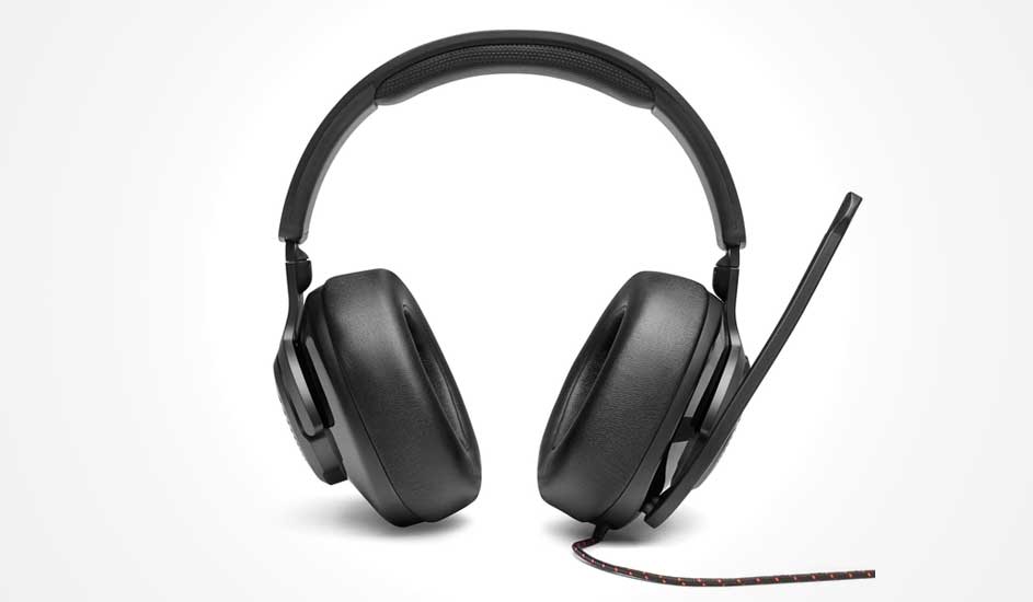 A chunky black gaming headset faces front, with deep cushioned earcups, a slim boom microphone and a braided cable resting below.