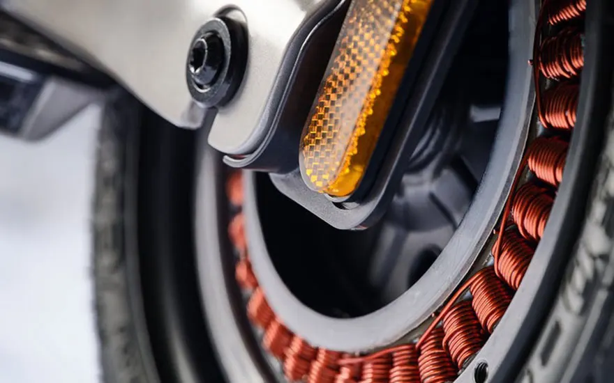 Close-up van een elektrische motor met oranje koperdraden en gele reflectoren, toont de interne technische componenten van een e-step.