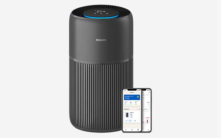 Close up of a dark grey Philips PureProtect Quiet 2200 air purifier with a glowing control ring on top, naast een smartphone die de bedieningsapp weergeeft.