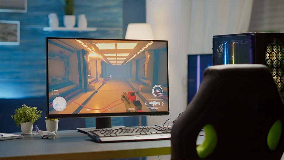 A computer monitor displays a car racing game, a keyboard sits in front of the screen, and a gaming chair is visible.