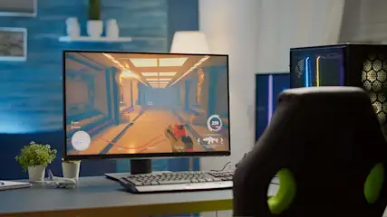 A computer monitor displays a car racing game, a keyboard sits in front of the screen, and a gaming chair is visible.