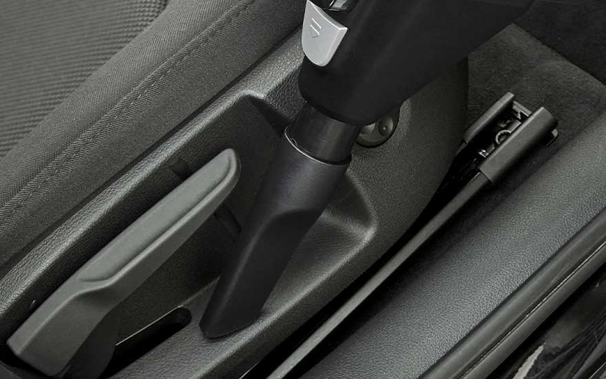 Close-up of a vacuum cleaner nozzle being used to thoroughly clean hard-to-reach areas inside the car for optimal cleanliness.