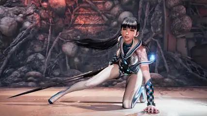 Een vrouw in een blauw-wit kostuum knielt met een zwaard op een stenen vloer tegen een achtergrond van rotsen en planten.