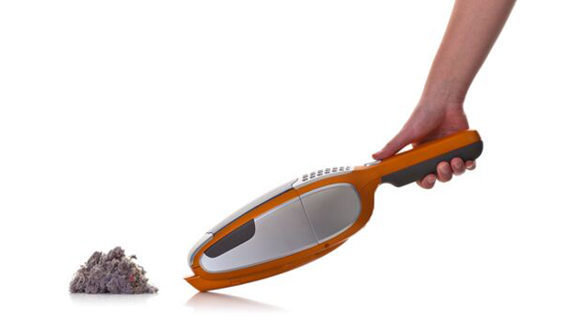 Een oranje kruimeldief wordt boven een hoopje stof gehouden. De achtergrond is wit.