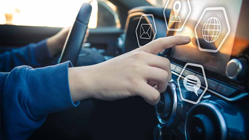 Een hand bedient een touchscreen in een auto met pictogrammen voor e-mail, locatie, internet en chat.