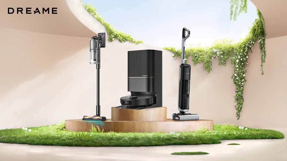 Drie zwarte stofzuigers staan op een houten platform met groen gras, tegen een beige achtergrond met planten.