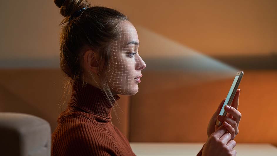 Een vrouw in profiel houdt een telefoon vast met een raster over haar gezicht en een lichtstraal die van de telefoon afkomt.