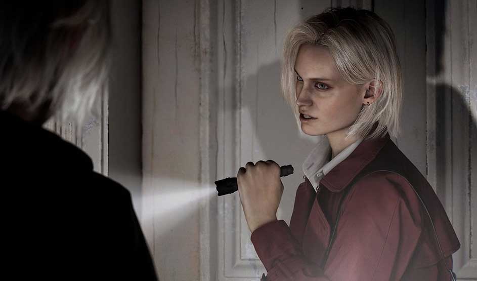 C’est un jeu vidéo : une blonde tient une lampe torche près d’une porte en bois et fixe, tendue, une silhouette sombre au premier plan.