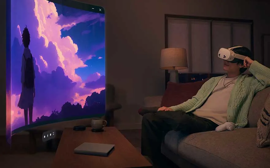 A person sits relaxed on a couch, using a VR headset to watch a huge virtual screen with an anime-inspired landscape.