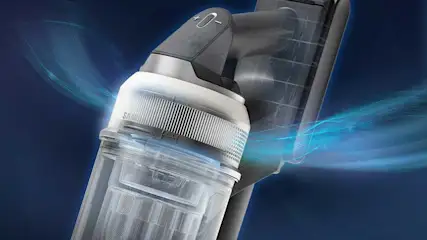 Close-up of a cordless vacuum cleaner, showing its clear dust container while blue airflows highlight the strong suction performance.