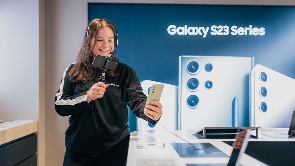 Een vrouw met een headset filmt met twee telefoons de Samsung Galaxy S23 serie.