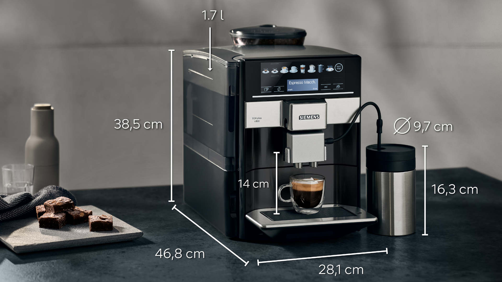Espressomachine met maatindicaties, een kop koffie, een isoleerbeker, een fles, een glas en brownies op een plank.