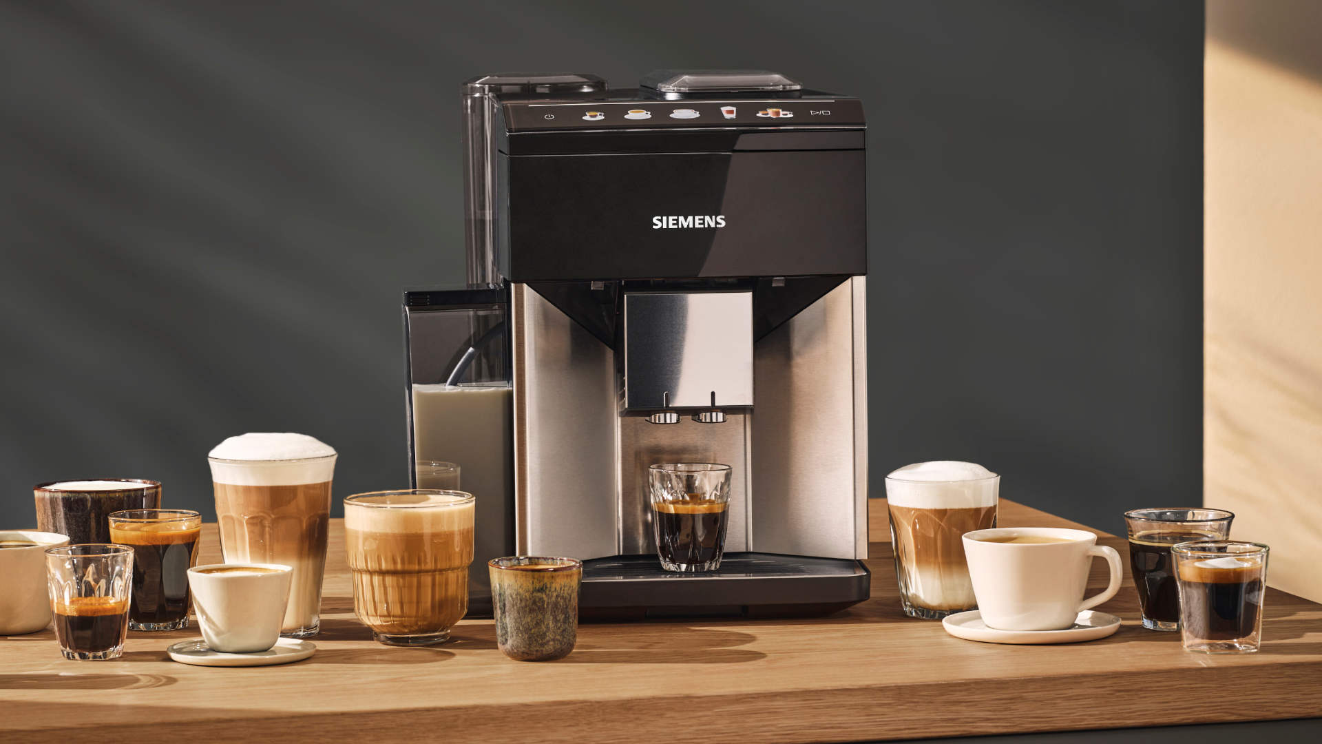 Een Siemens koffiemachine staat op een houten tafel, omringd door diverse glazen en kopjes koffie en melk.