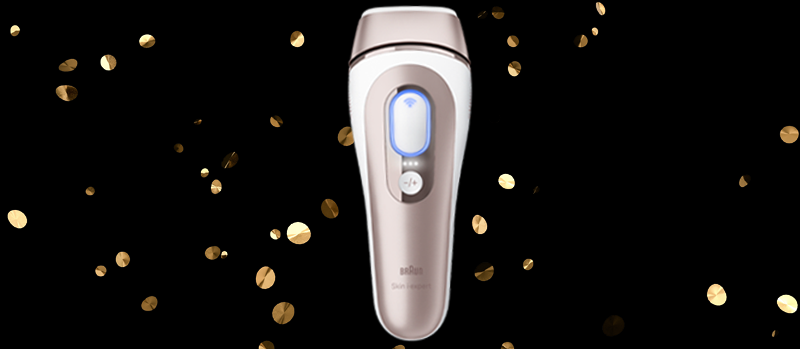 Op de afbeelding staat een Braun ontharingsapparaat met goudkleurige accenten, omringd door gouden confetti op een zwarte achtergrond.