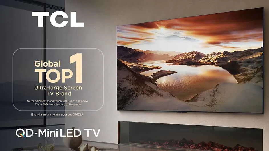 TCL QD-Mini LED TV aan de muur boven een open haard. Het scherm toont een zonsondergang boven bergen en water. Tekst: "Global Top 1 TV Brand".