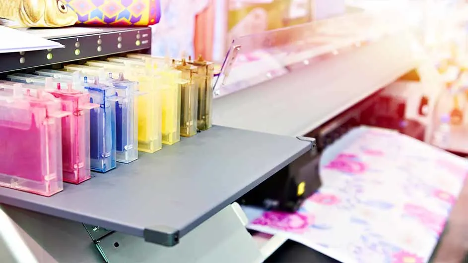 Een printer met kleurrijke inktpatronen in roze, blauw en geel. Papier met een bloemenprint komt uit de printer.