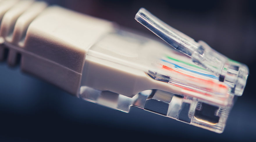 Een close-up van een doorzichtige RJ45-connector met zichtbare blauwe, groene en rode draden tegen een donkere achtergrond.