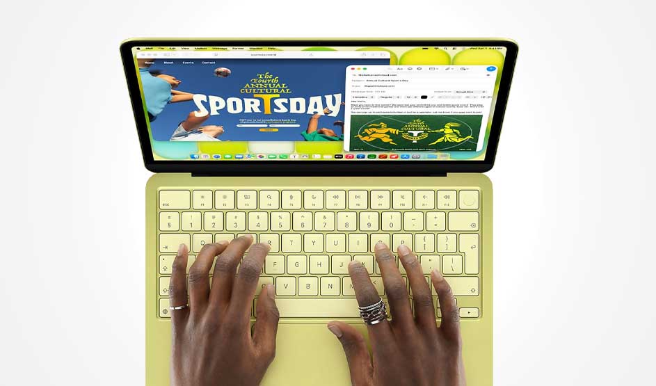 Bovenaanzicht van gele laptop waarop handen typen; op het scherm staan kleurrijke sportdagwebsite en mailvenster naast elkaar geopend.