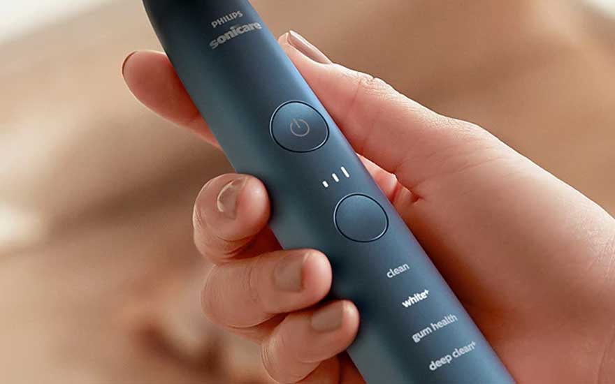 Close-up van een hand die een blauwe Philips Sonicare vasthoudt, waarbij de poetsstanden duidelijk op het handvat zichtbaar zijn.