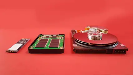Drie opslagapparaten: een M.2 SSD, een SATA SSD en een harde schijf liggen op een rode achtergrond.