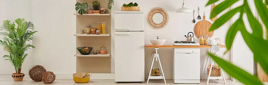 Een lichte keuken met witte koelkast, open planken, kamerplanten, rieten manden, een wasbak en houten details in rustige stijl.