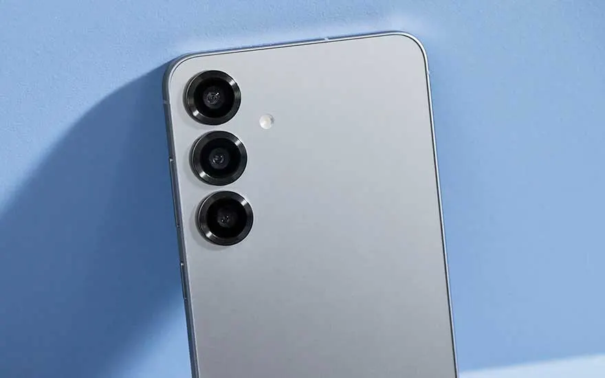Close-up van de zilverkleurige achterkant van een Samsung-smartphone, met drie verticale cameralenzen en een kleine flitser erboven.