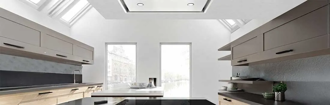 Bright modern kitchen with skylights, tall windows, sleek grey cabinets and a glossy black island.
