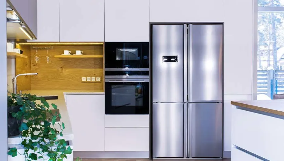 Moderne keuken met witte kasten, roestvrijstalen koelkast, zwarte oven en een houten accentmuur met planken en keukengerei.