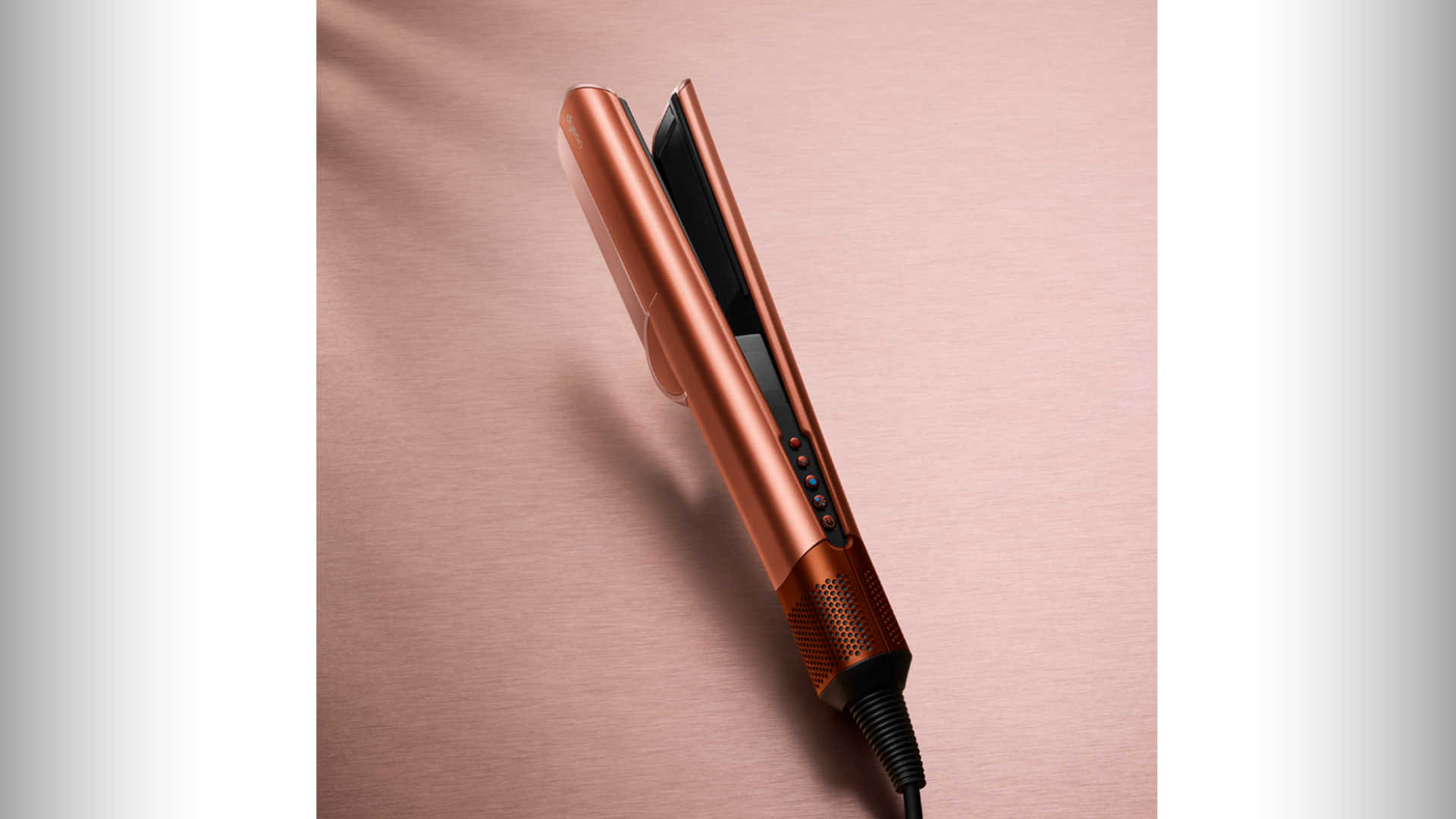 Roségouden stijltang met zwarte platen en bedieningsknoppen op een roze achtergrond.