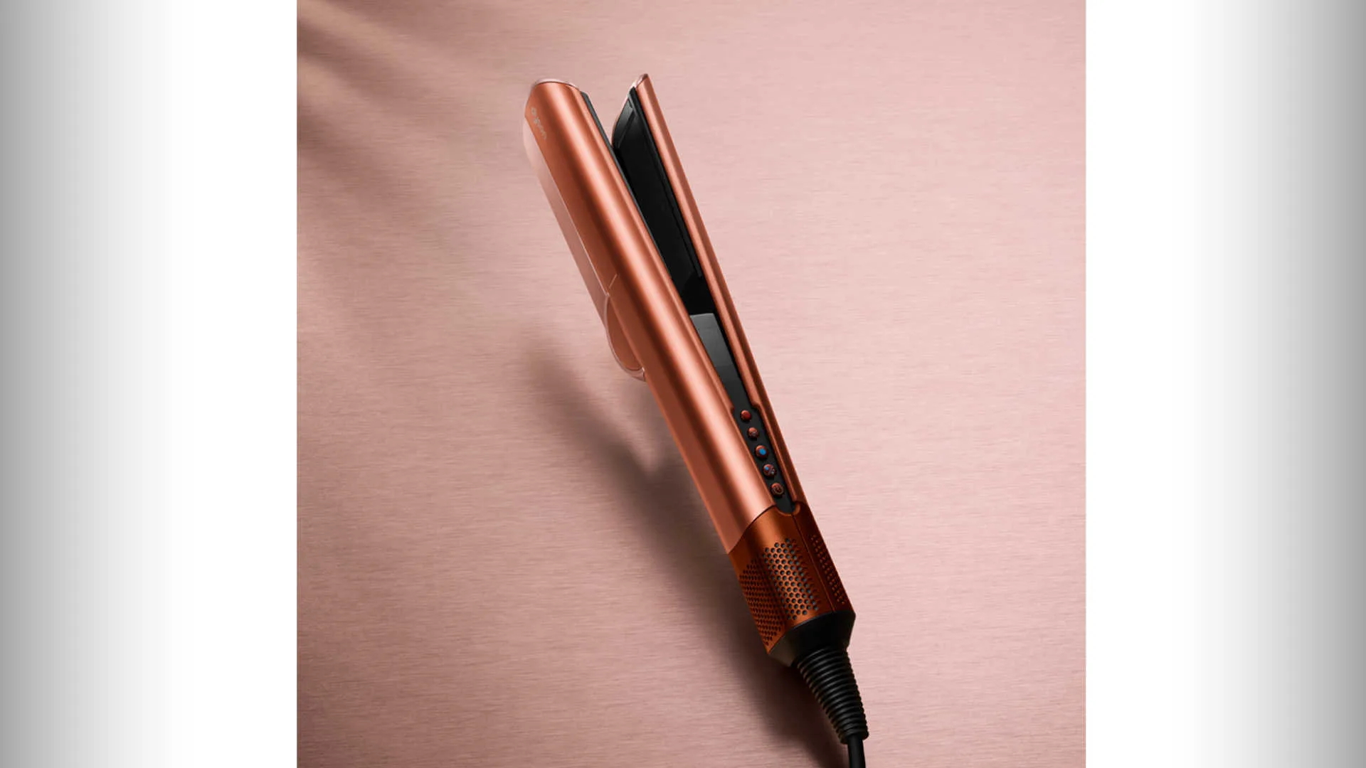 Roségouden stijltang met zwarte platen en bedieningsknoppen op een roze achtergrond.